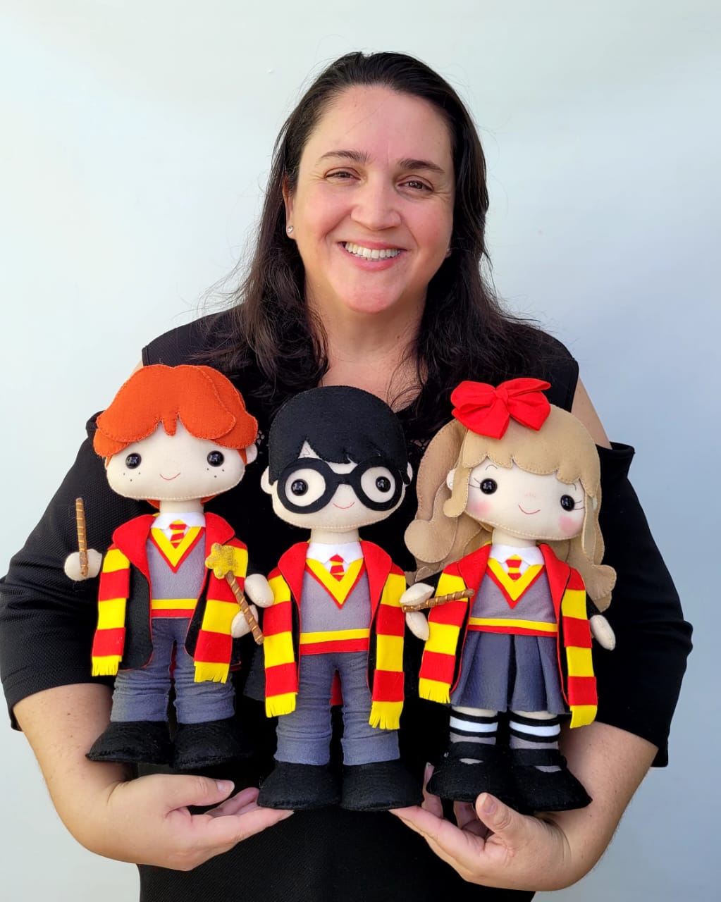 Daniela, criadora do Ateliê Mimos da Juju, segurando bonecos de feltro do Harry Potter